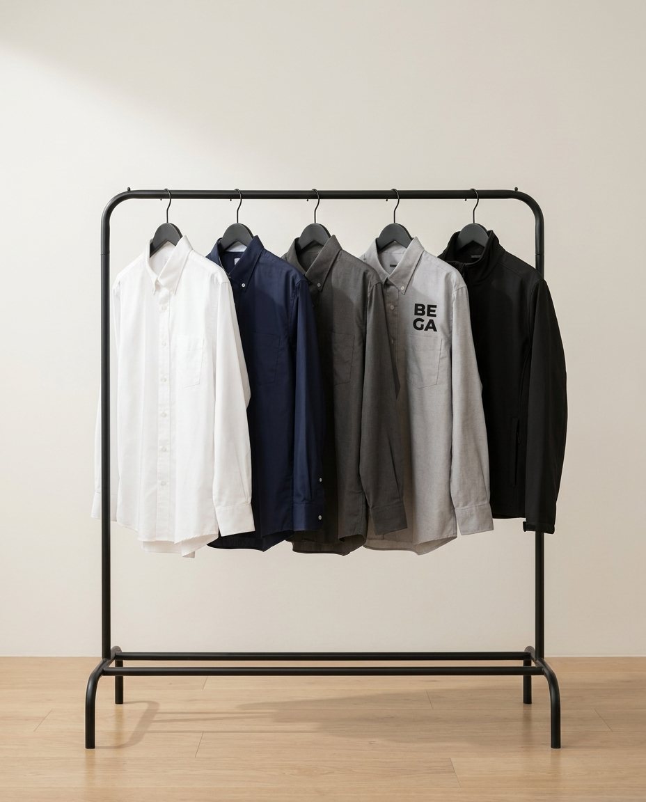 Camisas y chamarra de uniforme en un perchero, una con el logo de Bega bordado